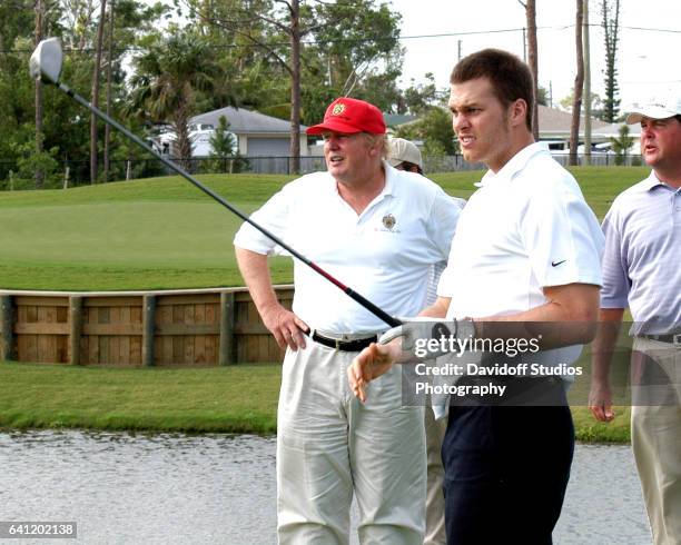 American football player Tom Brady tees off, watched by real estate developer Donald Trump , on the course at Trump International Golf Club, Palm...