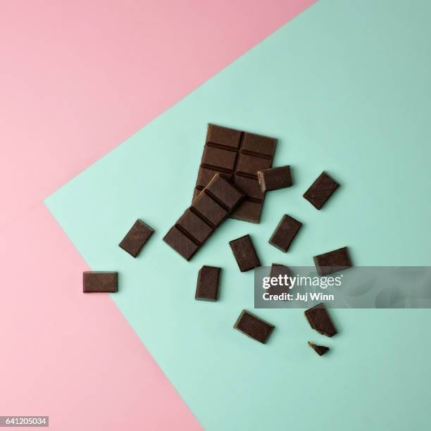chocolate pieces on color block background - cioccolato scuro foto e immagini stock