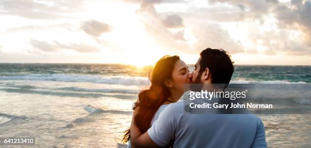 happy couple kissing on beach. - gary love stock pictures, royalty-free photos & images