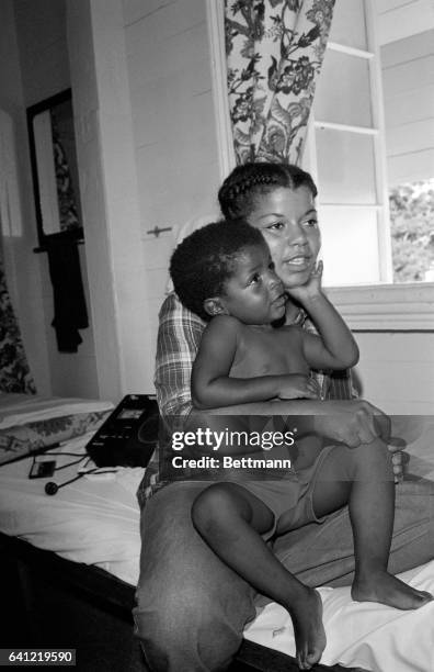 Three-year-old Jakarri Wilson, the youngest survivor of the mass-suicide-murder rites at Jonestown, strokes his mother's chin as she talks to newsmen...