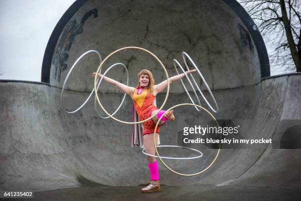 a hula hooping girl in a bright costume dancing with 7 hoops - woman twirling stock pictures, royalty-free photos & images