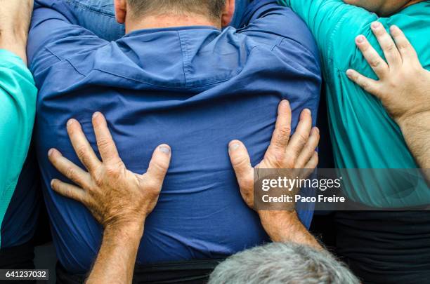 close-up of the back and the hands of the "castellers" who form the core of a catalan human tower - inzamelingsevenement stockfoto's en -beelden