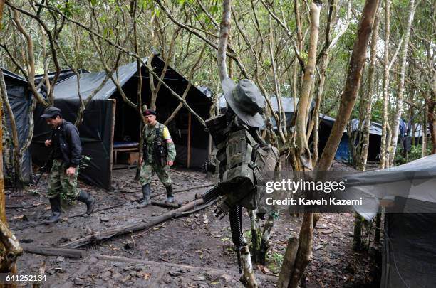 Genral view inside a demobilization camp where two FARC fighters pass by an automatic assault rifle and a vest hanging on a tree on January 17, 2017...