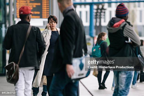 businesswoman with suitcase using smartphone - beengt stock-fotos und bilder