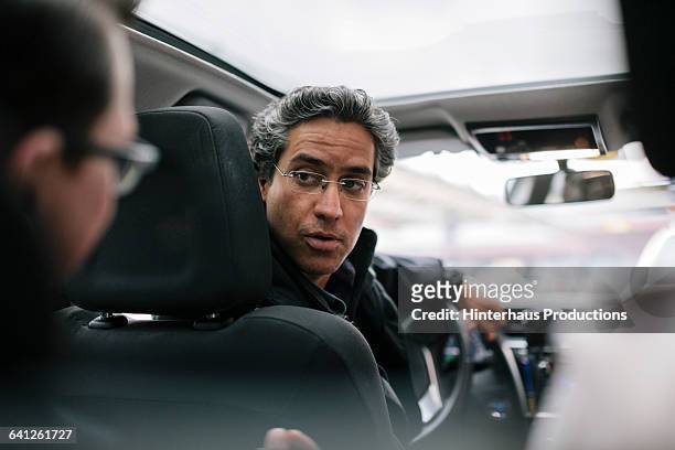 taxi driver talking to businessman - auto innenansicht stock-fotos und bilder