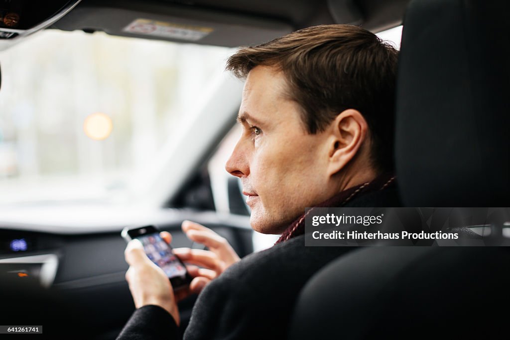 Mature Businessman with Smart phone in a taxi