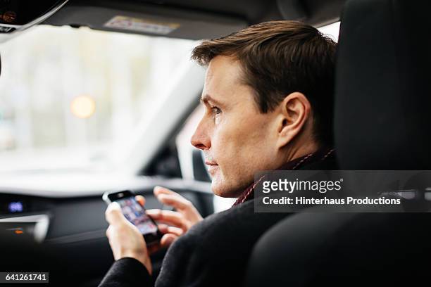mature businessman with smart phone in a taxi - passagerarsäte bildbanksfoton och bilder