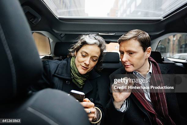 business people with smart phone inside taxi - man and woman and car stock pictures, royalty-free photos & images