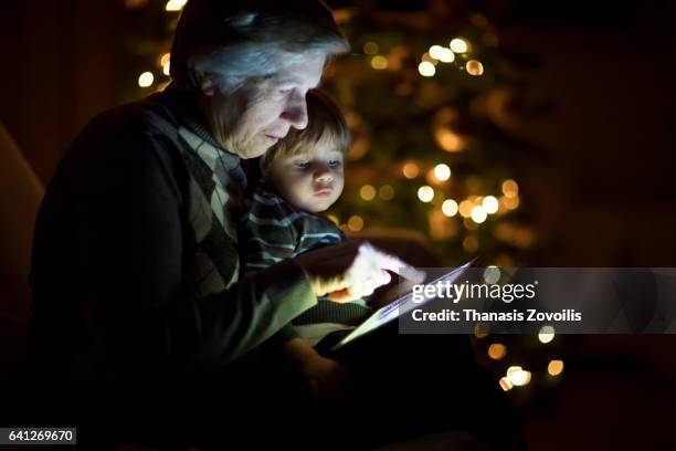 grandmother looking a digital tablet with her grandchildren - christmas dark stockfoto's en -beelden