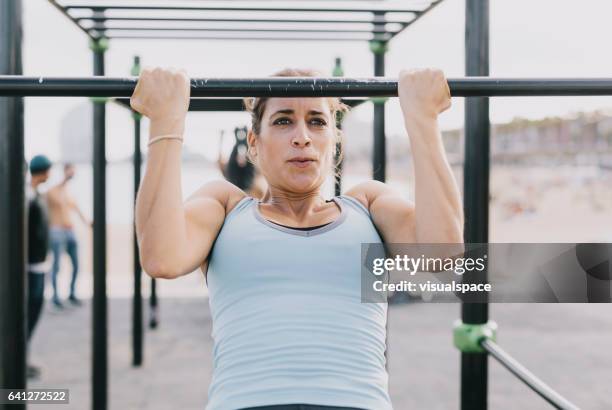 vrouw doet pull-ups op monkey bars voor fitness - chin ups stockfoto's en -beelden