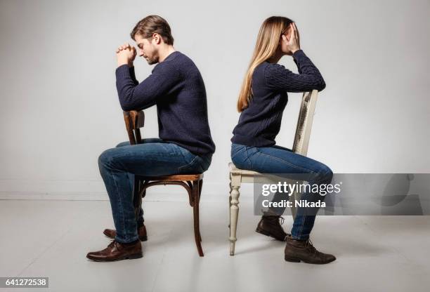 seitenansicht des depressiv paar sitzen rücken an rücken auf stühlen - kommunikationsproblem stock-fotos und bilder