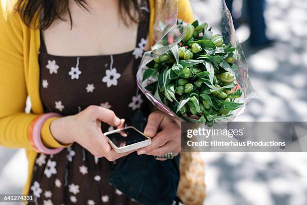 woman using mobile phone on city street - unter dem arm stock-fotos und bilder