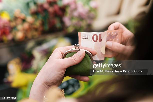 woman paying for flowers with 10 euro bill - euros fotografías e imágenes de stock