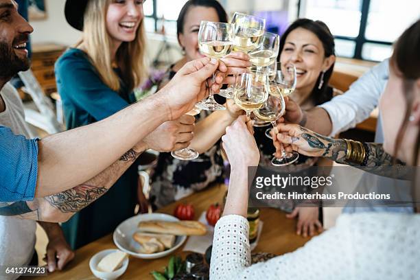 friends toasting  at a dinner party - wine cheers stockfoto's en -beelden