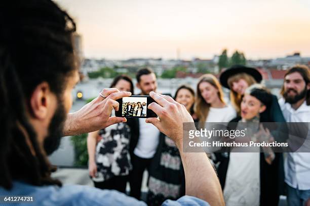 young man taking pictures of his friends - organized group photo stock pictures, royalty-free photos & images
