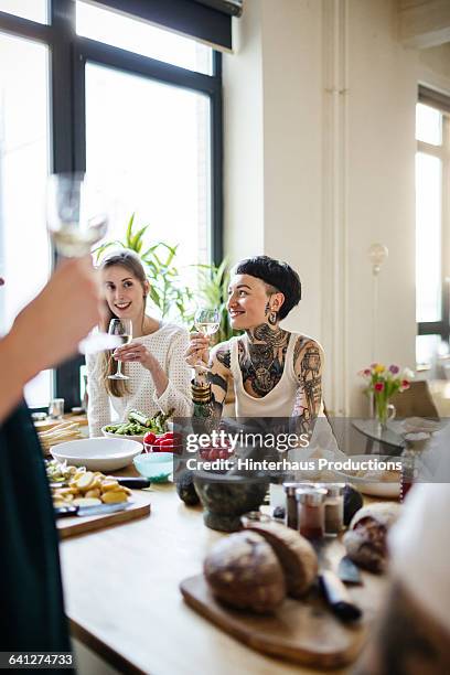 young women talking at dinner party - kochen freunde stock-fotos und bilder