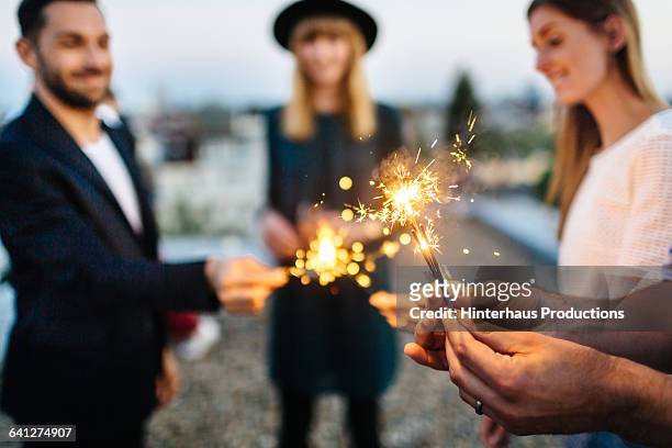 close up of hands with sparklers - rooftop stock-fotos und bilder