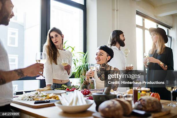 group of friends drinking wine and talking - dinner party at home stockfoto's en -beelden