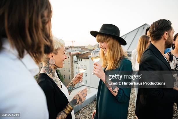 two tattooed friends at rooftop party - drinking wine stock-fotos und bilder