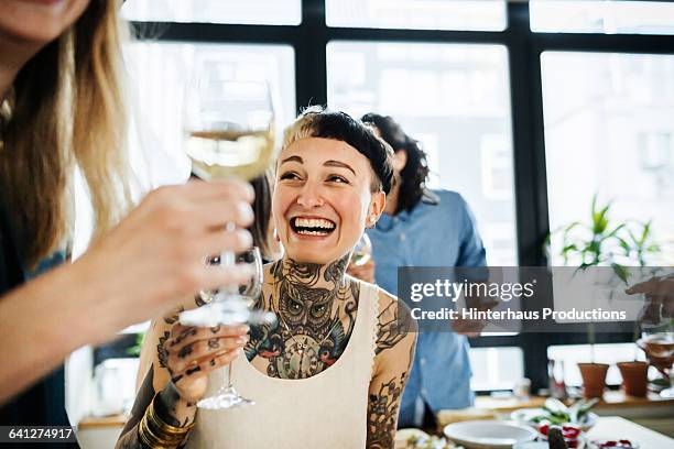tattooed woman having fun during dinner party - drinking wine fotografías e imágenes de stock