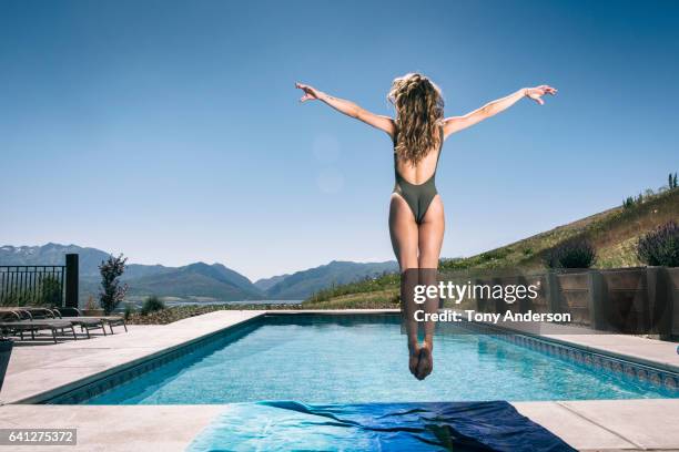 young jumping near pool in mountain valley rear view - swimming pool jump stock pictures, royalty-free photos & images
