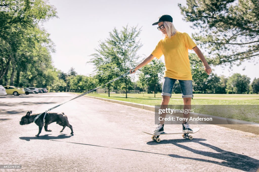Young woman on skateboard being pulled by her dog
