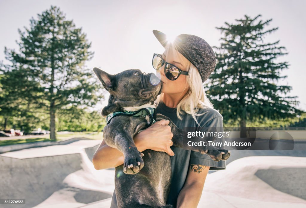 Young woman kissing her dog at skatepark