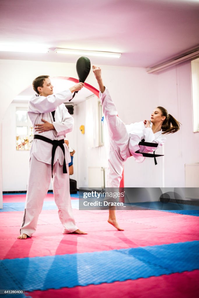 Concurrerende taekwondo meisje op opleiding, ronde schoppen focus mat