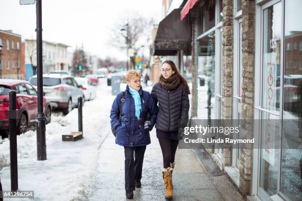 a girl and a senior woman walking on a sidewalk  during winter - montreal street stock pictures, royalty-free photos & images