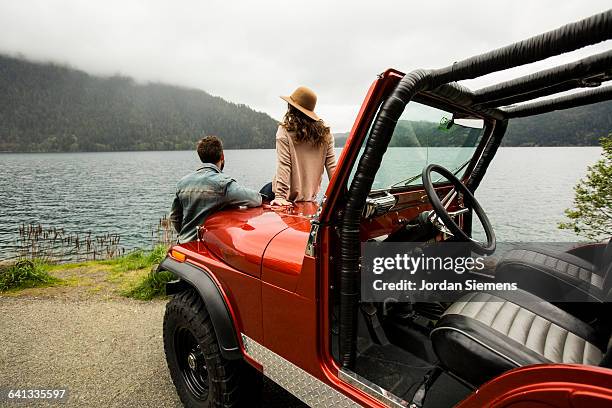 a couple in a convertible. - woman sitting on mans lap stockfoto's en -beelden