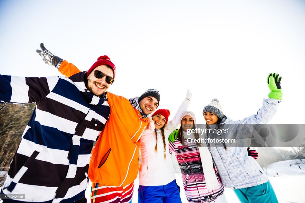 Young friends in ski-wear with arms raised