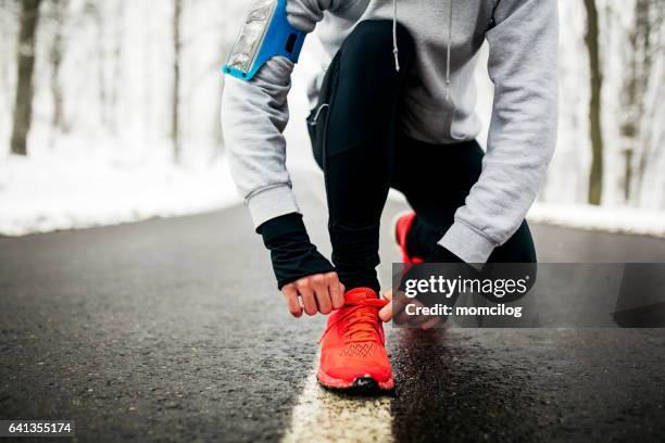 junge läufer seine schnürsenkel zu binden - wintersport stock-fotos und bilder