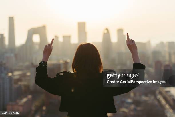 rear view of woman giving middle finger in city - antisocial stockfoto's en -beelden