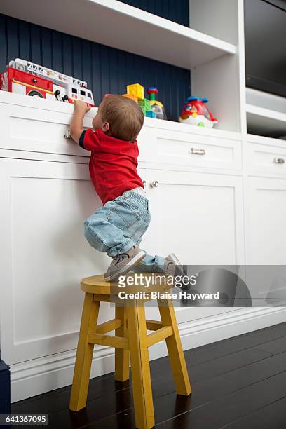 infant boy climbing on stool - seat perilous fotografías e imágenes de stock
