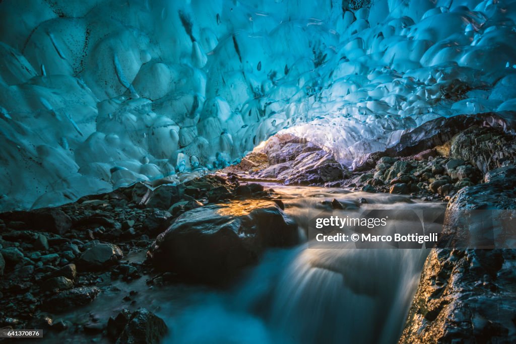 Flowing river inside a crystal ice cave in winter. Iceland.