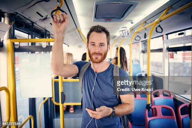 young man with headphones on a bus - autobus foto e immagini stock