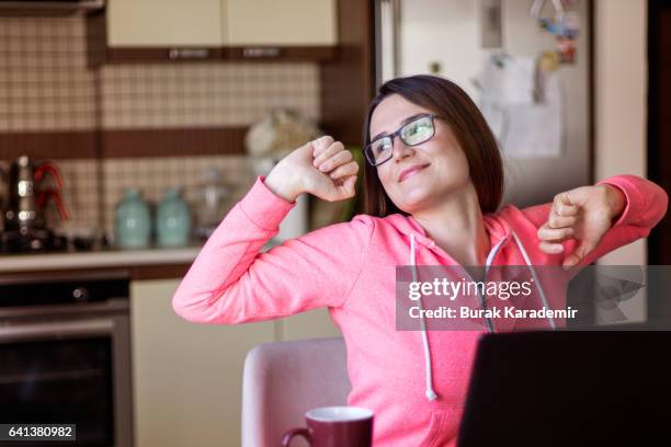 tired young woman stretching and yawning after working day - yawn office stock-fotos und bilder