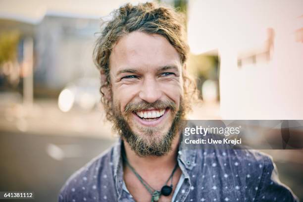 young bearded man smiling - lachen stock-fotos und bilder