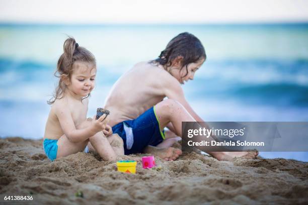cute girl and boy enjoying sand on the beach - 2 girls 1 sandbox stock pictures, royalty-free photos & images