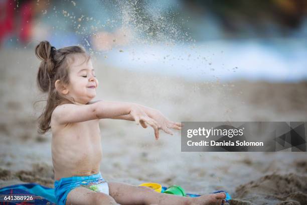 cute girl enjoying sand on the beach - sandbox stock-fotos und bilder