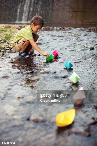 little boy playing paper boats in stream - origami boat stock pictures, royalty-free photos & images