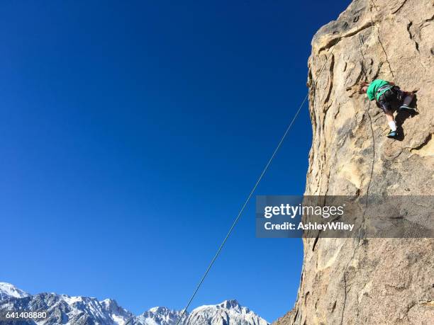 jongen klimmen op het gezicht van een rots in de bergen - extreme hug face stockfoto's en -beelden