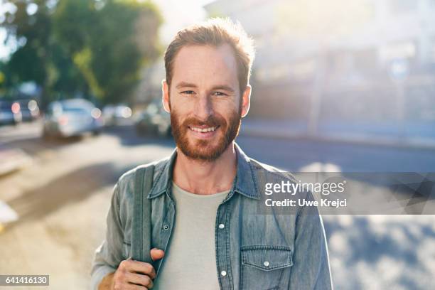 smiling young man on the street - street fotografías e imágenes de stock