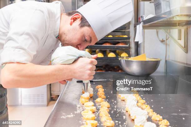 chef pâtissier, remplissage des petites pâtisseries avec poche à douille - pâtissier photos et images de collection