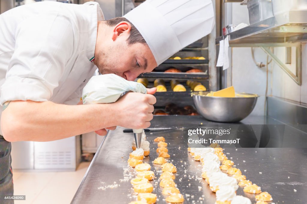 Pasticcere ripieno di piccoli pasticcini con sacchetto di pasticceria