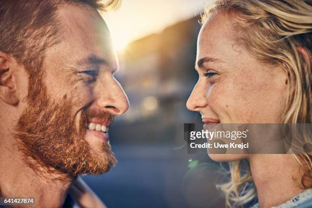 young couple smiling at each other, close up - faccia a faccia foto e immagini stock