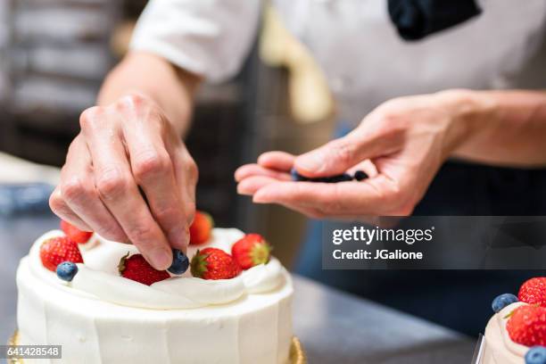 añadir arándanos para una torta de panadero - decorating a cake fotografías e imágenes de stock