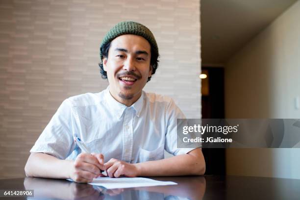 smiling young man signing a contract - escritura japonesa imagens e fotografias de stock