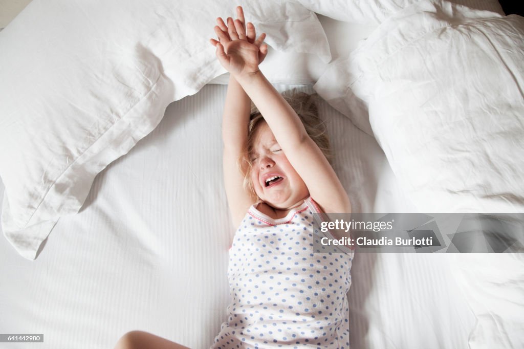 Little girl crying in bed