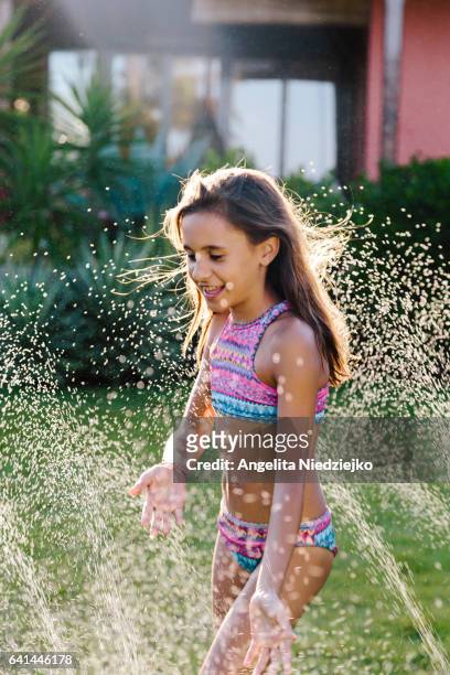 girl playing in the water on the lawn - relaxamento stockfoto's en -beelden